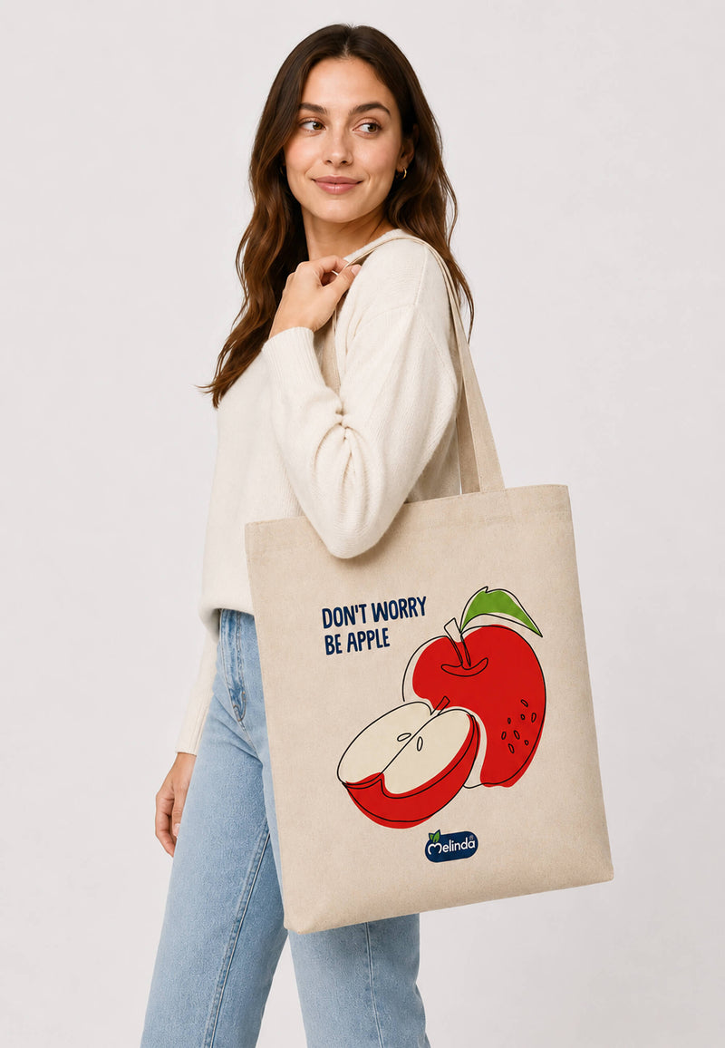 Tote Bag Organic Premium Melinda, stampa con mela rossa e scritta Be Apple, indossato