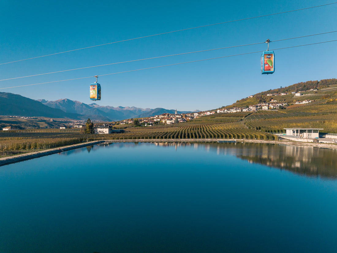 Cabine della funivia Melinda sopra un lago e i meleti